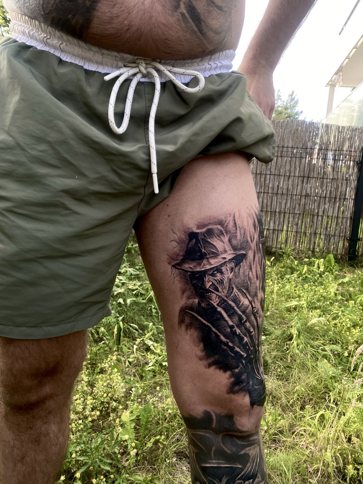 Realistyczny tatuaż portret Freddy'ego Kruegera na udzie w stylu dark realism