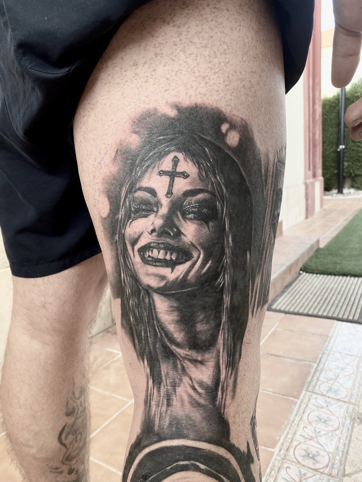Realistyczny tatuaż portret uśmiechniętej kobiety w stylu dark realism na udzie